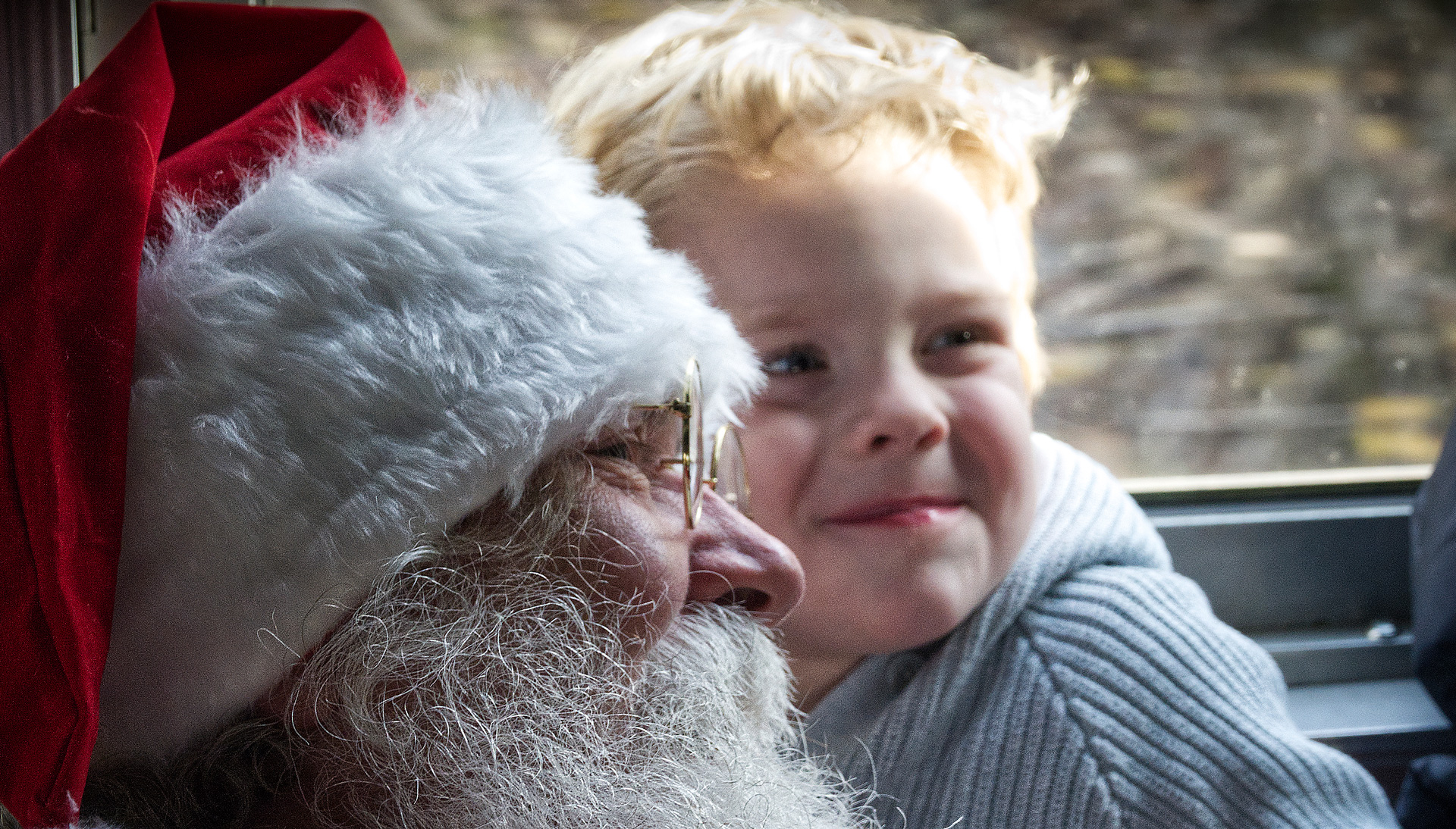 A close up of Santa Claus and a little boy's face smiling