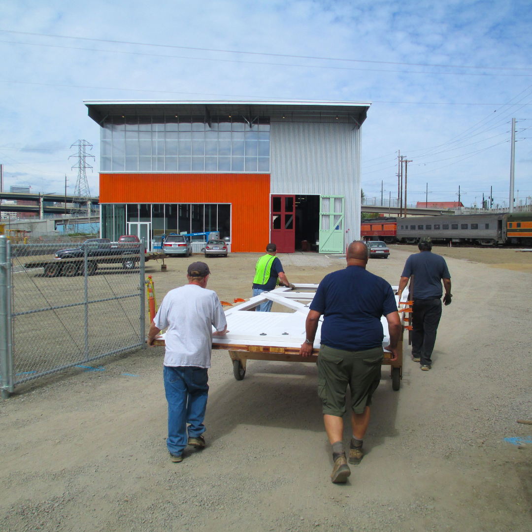 4 men carrying a piece of the Oregon Rail Heritage Center Enginehouse towards the building in construction 